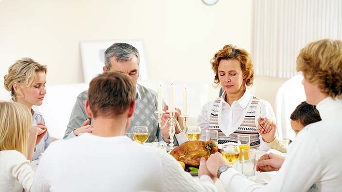 Family sitting at table and praying.