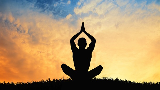 Person meditating against a sunset sky