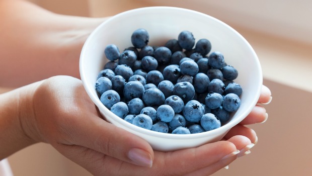 Hands holding bowl of blueberries