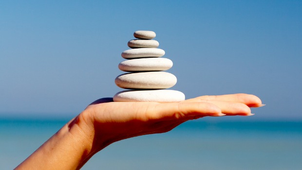 Stones balanced on a hand in front of ocean