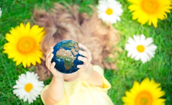 Little girl holding up a globe.