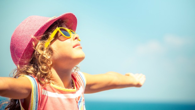 Little girl in hat and sunglasses on the beach