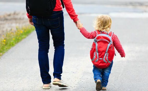 A parent and child walk to school