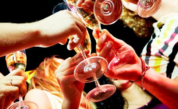 People clinking wine glasses at a party.