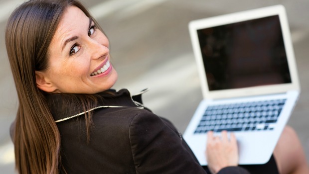 Smiling woman looking up from a laptop computer.