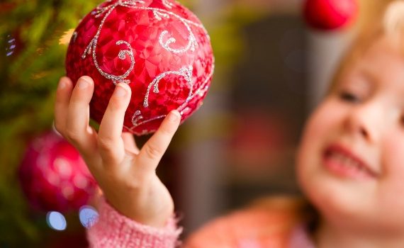 Little girl holding Christmas ornament.