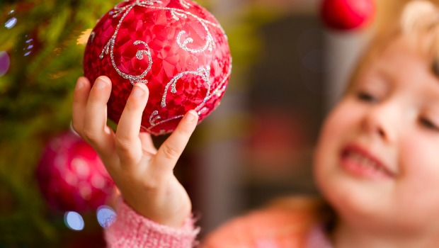 Little girl holding Christmas ornament.