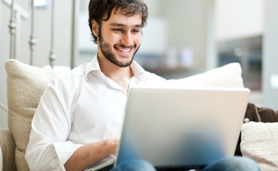 Attractive bearded man checks his social media on a laptop computer.