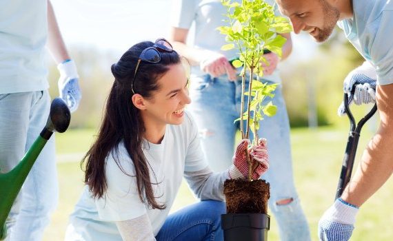 Woman volunteering in a garden with a group of people.