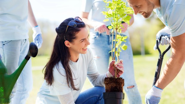 Woman volunteering in a garden with a group of people.