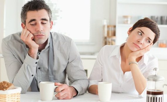 Married couple having breakfast and looking bored.