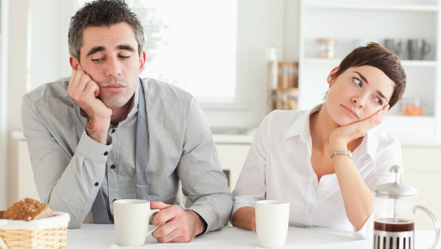 Married couple having breakfast and looking bored.