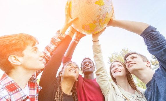 Diverse group of people holding a globe.