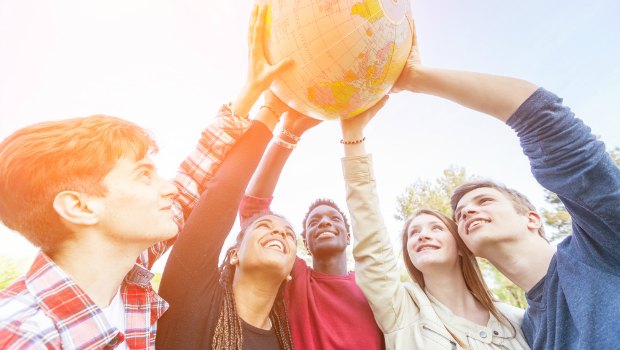 Diverse group of people holding a globe.