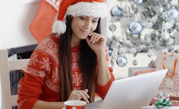 Woman sitting at a desk working on laptop with Christmas decor.