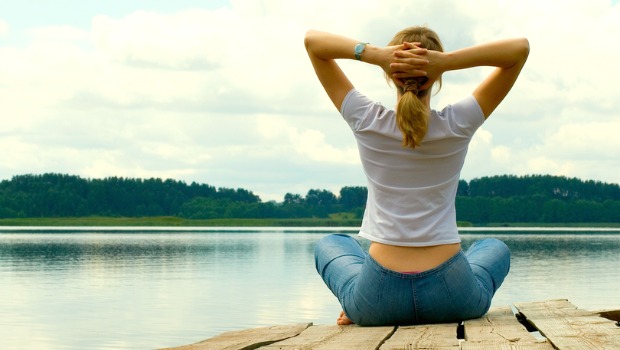 Woman meditating by a lake.