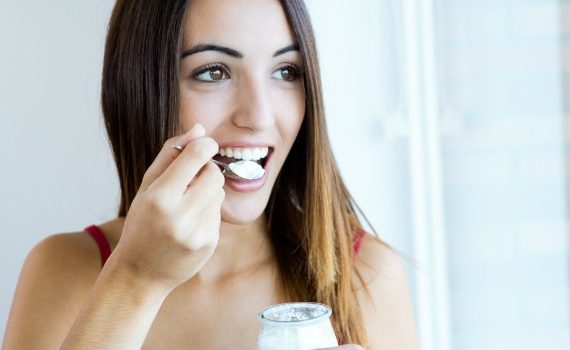 Woman eating spoonful of yogurt.