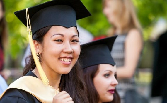 College grad smiling at the camera.