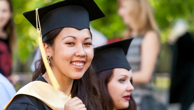 College grad smiling at the camera.