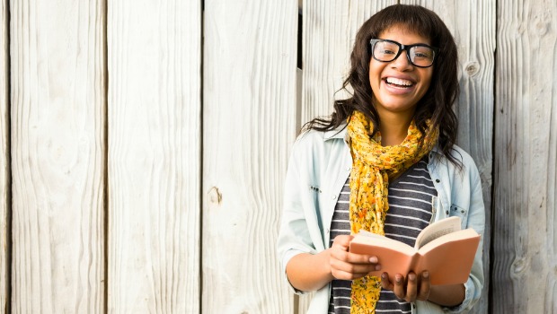 Young woman holding a book and smiling.