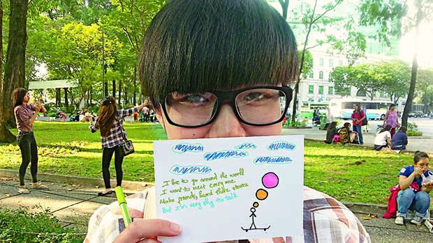 Boy with glasses holding up note and drawing.