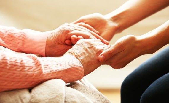 Younger woman holding older woman's hands.