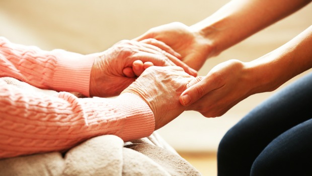 Younger woman holding older woman's hands.