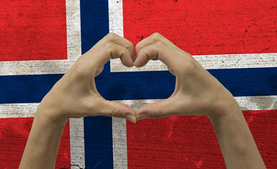 The Norwegian flag with hands in a heart-shape in front of it.