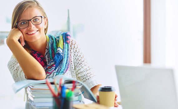 Woman with a stack of books on her desk.