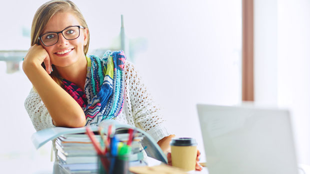 Woman with a stack of books on her desk.