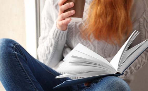 Red-haired woman reading a book.