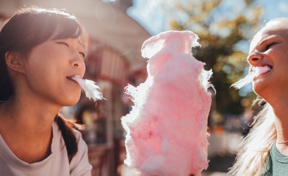 Two young women eating cotton candy.