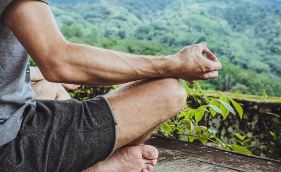 Man meditating on a mountain.