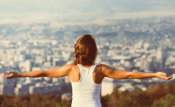 Woman spreading her arms on a hill.