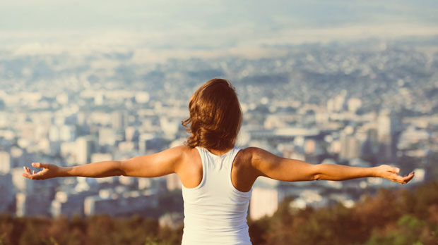 Woman spreading her arms on a hill.