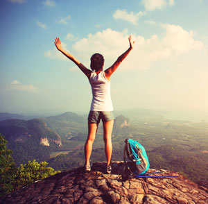 Strong woman on top of a mountain.