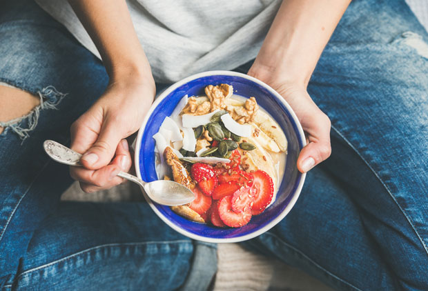 Woman eating bowl of granola.