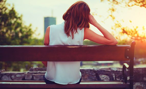 Pensive woman sitting on a bench.