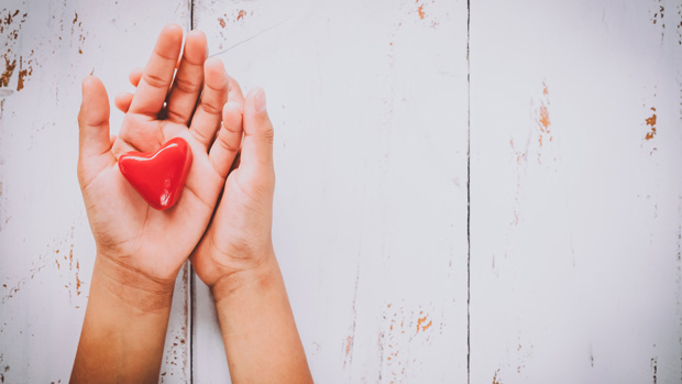 Hands holding a small heart.