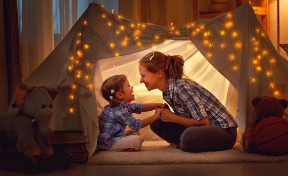 Mom and daughter in a tent indoors.