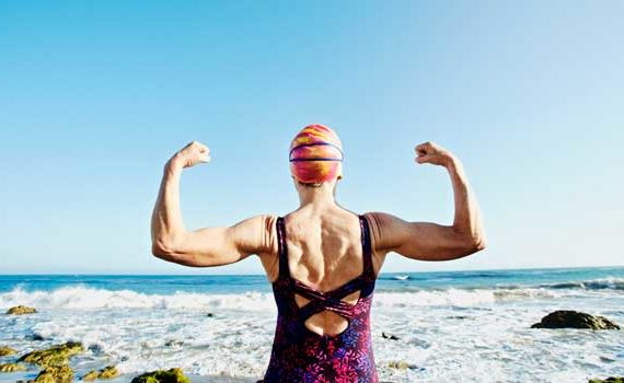 Older lady flexing her muscles before a swim