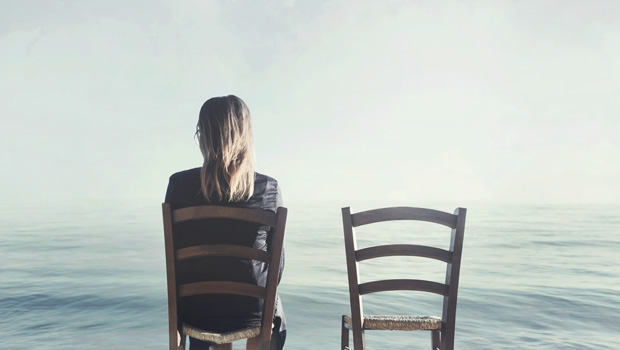 alone woman sitting next to her lover's empty chair