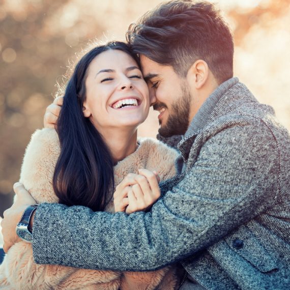 Happy young couple hugging and laughing outdoors.