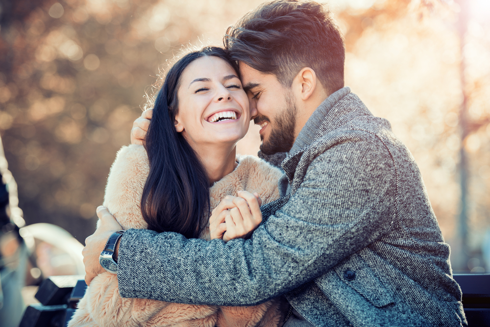 Happy young couple hugging and laughing outdoors.