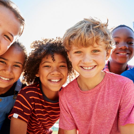 Close up of pre-teen friends in a park smiling to camera