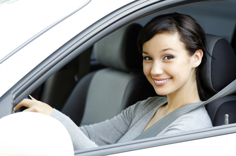 female driver in white car smiling to you.