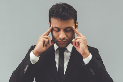 Businessman in classic suit is touching his temples while concentrating