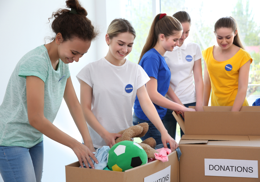 Young volunteers with boxes of donations indoors