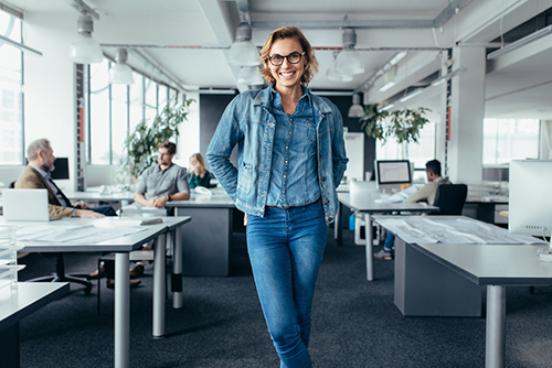 Cheerful businesswoman standing in office environment. Young female executive standing and looking at camera.