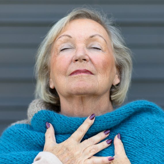 Attractive senior woman savoring the moment standing with her eyes closed and head tilted back with a serene expression